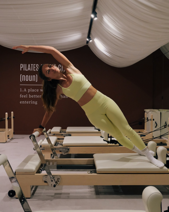 Exercice de planche latérale sur machine Pilates Reformer au studio de Saint-Étienne